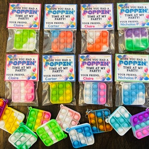 May include: A set of ten colourful pop-it fidget toys packaged in clear plastic bags with personalised tags that say "Hope you had a poppin' time at my party!"  The tags include the name of the party host and the phrase "Your friend."