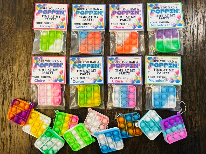 May include: A set of ten colourful pop-it fidget toys packaged in clear plastic bags with personalised tags that say "Hope you had a poppin' time at my party!"  The tags include the name of the party host and the phrase "Your friend."