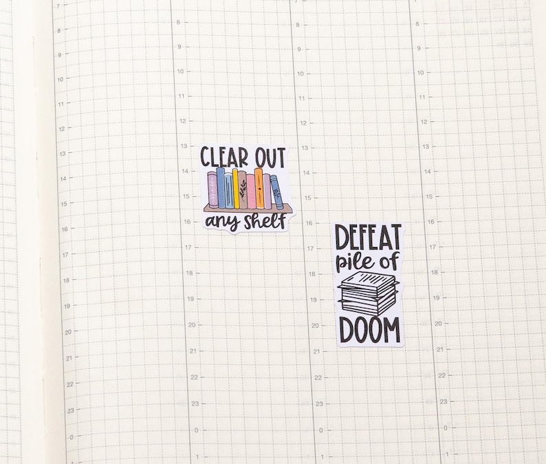 May include: Two colourful stickers with book-themed sayings. The first sticker says "Clear out any shelf" and features a bookshelf with colourful books. The second sticker says "Defeat pile of doom" and features a stack of books.