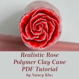 Könnte beinhalten: Eine Nahaufnahme einer roten Polymer Clay Cane mit einem realistischen Rosenmuster. Die Cane ist rund und hat eine glatte Oberfläche. Die Rose ist in voller Blüte und hat ein zartes, geschichtetes Design. Der Text "Realistic Rose Polymer Clay Cane PDF Tutorial by Nancy Kluz" ist unter dem Bild gedruckt.