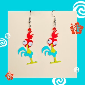 Puede incluir: Un par de pendientes colgantes con un gallo de dibujos animados con detalles rojos, amarillos y azules. El gallo tiene ojos grandes y blancos y una cresta roja brillante.