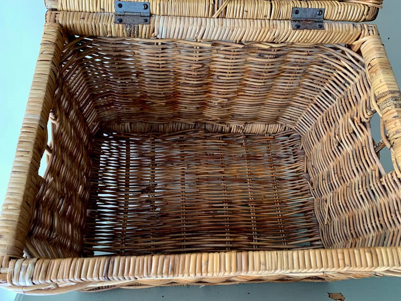 Peut inclure: Panier en osier ouvert avec couvercle &agrave; charni&egrave;re. Fabriqu&eacute; en osier tiss&eacute; brun clair et fonc&eacute;. Le couvercle est fix&eacute; par des charni&egrave;res m&eacute;talliques. Le panier est rectangulaire avec des coins arrondis et des poign&eacute;es sur les c&ocirc;t&eacute;s.