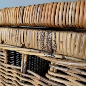 Peut inclure: Gros plan sur un panier en osier tress&eacute; de couleur marron clair naturelle. Le panier pr&eacute;sente une surface textur&eacute;e avec des motifs tiss&eacute;s verticaux et horizontaux. Le bord a un design arrondi et nervur&eacute;. Certaines zones montrent des signes d'&acirc;ge et d'usure.