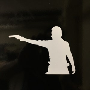 May include: A white silhouette of a person holding a gun, pointing it to the right. The person is wearing a shirt and pants. The background is black.