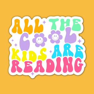May include: A colorful sticker with the text "All the cool kids are reading" in a retro font. The text is in a rainbow of colors, with flowers and stars scattered around it.