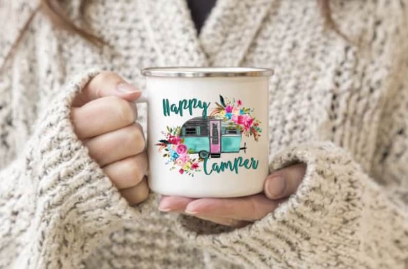 May include: White enamel mug with a teal and pink camper van surrounded by flowers and the text "Happy Camper".