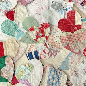 May include: A collection of handmade fabric hearts in various sizes and patterns. The hearts are made from a variety of fabrics, including floral prints, stripes, and solid colors. The color palette includes red, pink, blue, green, and white.