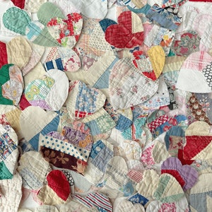 May include: A collection of heart-shaped fabric patches in various colors and patterns. The patchwork includes floral, striped, and solid fabrics in shades of red, blue, green, and white. The hearts are arranged closely together, creating a textured surface.