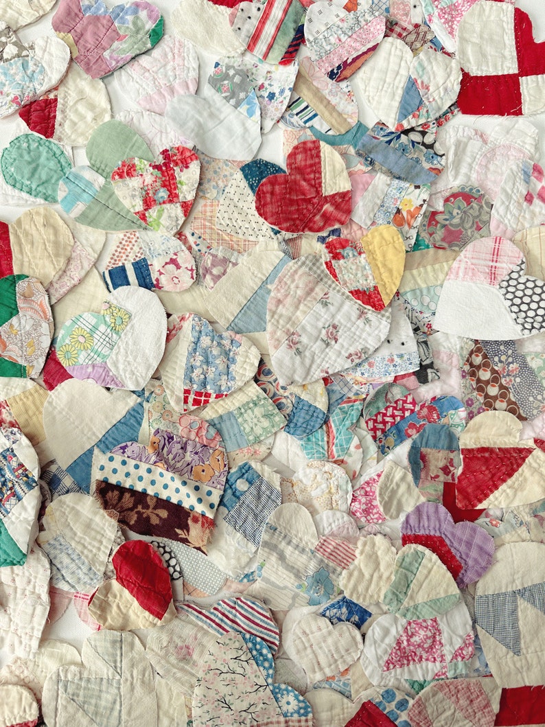 May include: A collection of heart-shaped fabric patches in various colors and patterns. The patches are made from different fabrics, including floral prints, stripes, and solid colors. The hearts are arranged closely together, creating a textured surface.