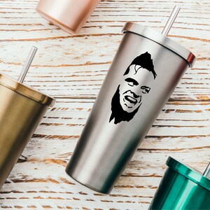 May include: A stainless steel tumbler with a black and white silhouette of a man's face. The tumbler has a lid and a straw.