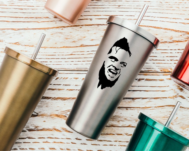 May include: A stainless steel tumbler with a black and white silhouette of a man's face. The tumbler has a lid and a straw.