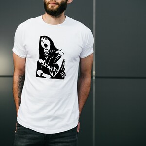 May include: White t-shirt with a black and white graphic print of a woman with long hair screaming.