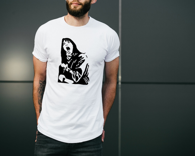 May include: White t-shirt with a black and white graphic print of a woman with long hair screaming.