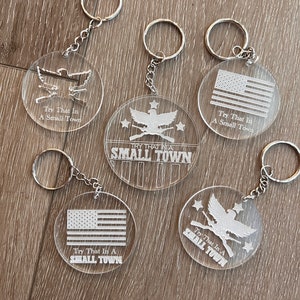 May include: Five clear acrylic keychains with a white design. Each keychain features a different design, including an eagle with guns, an American flag, and the text "Try That In A Small Town".