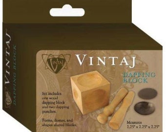 Könnte beinhalten: Ein Satz aus einem hölzernen Dapping-Block mit zwei hölzernen Dapping-Stanzern. Der Satz ist mit "Vintaj Dapping Block" beschriftet und enthält die Maße 2,25" x 2,25" x 2,25".