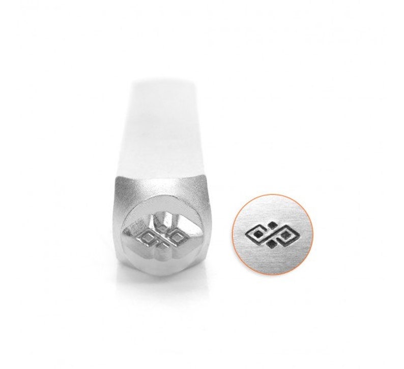 Op de afbeelding: Een zilveren metalen stempel met een geometrisch ontwerp. De stempel wordt gebruikt om indrukken in metaal te maken.