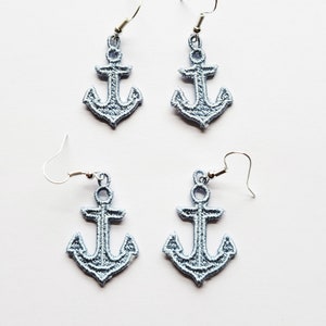 May include: A pair of silver dangle earrings with light blue anchor charms.