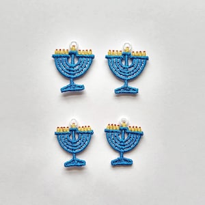 May include: Four blue embroidered menorahs with yellow candles, perfect for adding a festive touch to your Hanukkah decorations.
