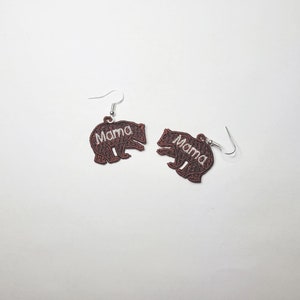 May include: A pair of brown bear-shaped earrings with the word "Mama" embroidered in white on each bear.