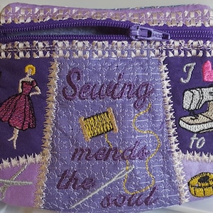 May include: Purple zippered pouch with embroidered designs. The pouch features a sewing machine, a spool of thread, scissors, a measuring tape, a woman in a dress, and the text "Vogue", "Sewing mends the soul", and "I love to sew".