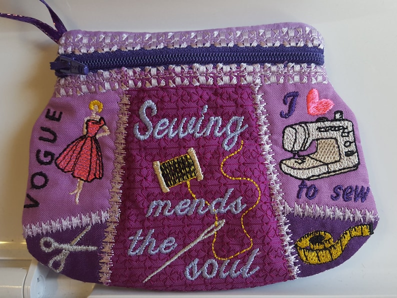 May include: Purple fabric zippered pouch with a patchwork design. The pouch features embroidered images of a sewing machine, scissors, thread, a measuring tape, and a woman in a dress. The text "Sewing mends the soul" and "I love to sew" are also embroidered on the pouch.