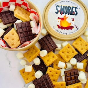 May include: A wooden bowl with a red and white checkered liner holds graham crackers, dark chocolate squares, and white marshmallows. Scattered around are more crackers, chocolate, and marshmallows. A round container with the text "S'Mores" and a campfire graphic is also present.