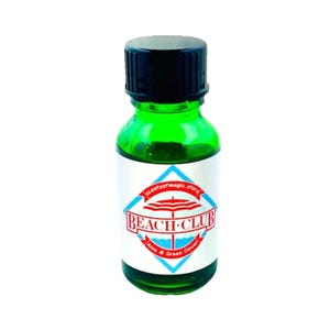May include: A small green glass bottle with a black lid. The bottle has a white label with a red and blue beach umbrella design and the text "BEACH-CLUB Aloe & Green Clover".