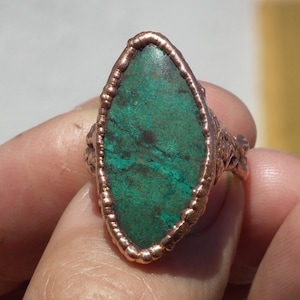 May include: A copper ring with a green gemstone set in a wire-wrapped setting.