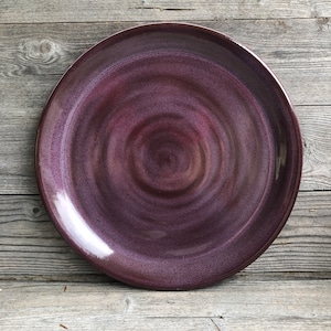 May include: A large, round, purple ceramic serving platter with a swirling, marbled design. The platter has a glossy finish and is perfect for serving appetizers, desserts, or other dishes.