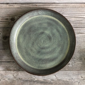 May include: A large, round, green and brown ceramic plate with a swirl pattern.