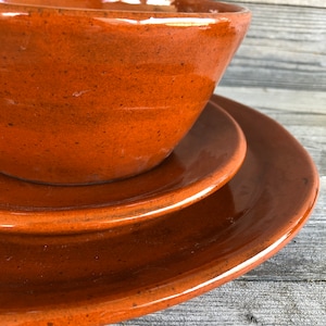 May include: A set of three brown ceramic dishes, including a bowl and two plates. The dishes have a speckled glaze and a rustic look.