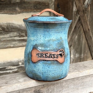 May include: Blue and brown ceramic dog treat jar with a bone-shaped lid that says "Treats".