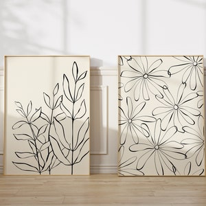 Puede incluir: Dos impresiones de arte en blanco y negro enmarcadas con dise&ntilde;os florales. La impresi&oacute;n de la izquierda presenta un grupo de hojas y tallos estilizados. La impresi&oacute;n de la derecha presenta un patr&oacute;n repetitivo de flores estilizadas.