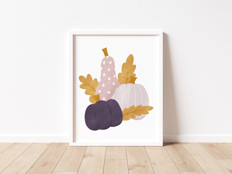 May include: A digital illustration of three gourds in a fall color palette. A pink gourd with white polka dots, a light purple gourd, and a white gourd with a ribbed texture. The gourds are surrounded by gold leaves.