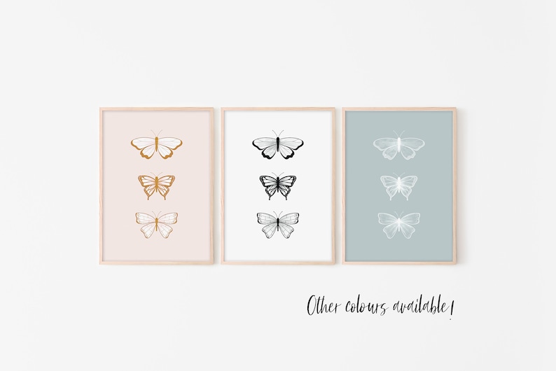 May include: Three framed butterfly art prints. The first print has a pink background with three gold butterflies. The second print has a white background with three black butterflies. The third print has a blue background with three white butterflies. Text: Other colours available!