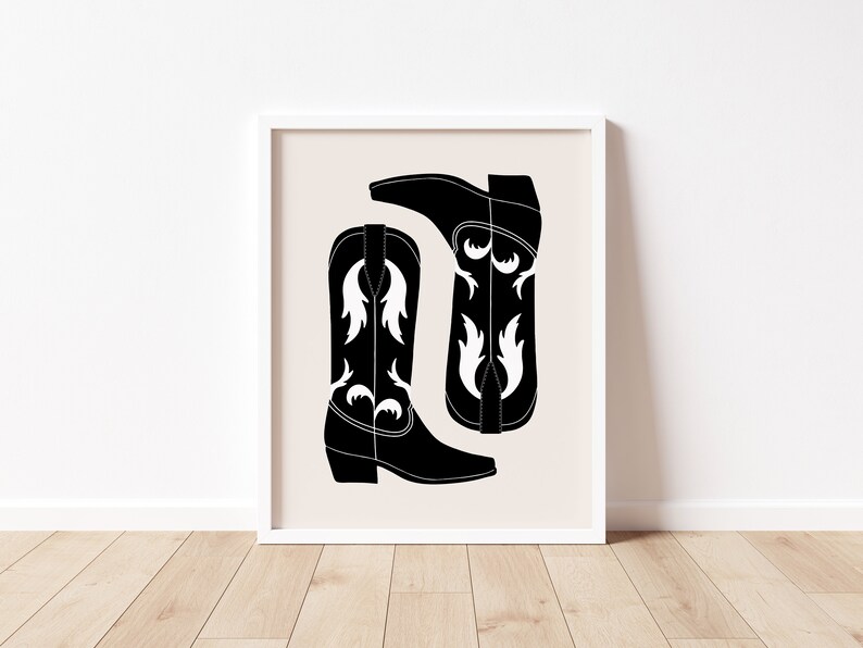 May include: A black and white illustration of two cowboy boots with a white floral design. The boots are on a beige background.
