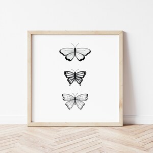 May include: A framed print featuring three black and white butterfly illustrations. Each butterfly has a unique wing pattern, set against a white background. The frame is a light wood color, adding a natural touch to the artwork.