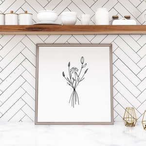 May include: A black and white line drawing of a bouquet of flowers in a simple, modern frame. The frame is on a white shelf with other decorative items.