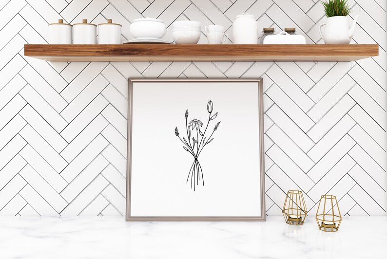 May include: A black and white line drawing of a bouquet of flowers in a simple, modern frame. The frame is on a white shelf with other decorative items.