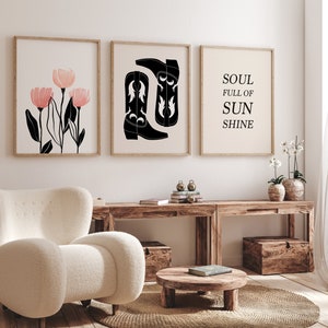 May include: Three framed prints on a white wall. The left print features a black and white illustration of pink flowers. The middle print features a black and white illustration of two cowboy boots. The right print features the text "SOUL FULL OF SUNSHINE".