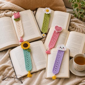May include: Four handmade crochet bookmarks featuring distinct designs: a pink tulip, a white daisy, a pink heart, a yellow sunflower, and a white smiling cloud. Each bookmark has a long, textured, open-work body and a small decorative tassel or star.