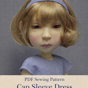 May include: A doll with blonde hair and a blue headband, wearing a blue and white striped cap sleeve dress. The image includes text that reads "PDF Sewing Pattern Cap Sleeve Dress for Big Stella 20".