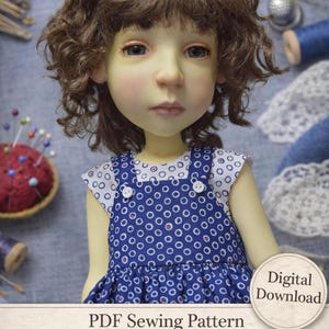 May include: A doll with brown curly hair and blue eyes wearing a blue and white polka dot dress. The dress has white buttons and a white collar. The image includes text that reads "PDF Sewing Pattern Lined Top & Pinafore - Big Stella by Connie Lowe - Digital Download."