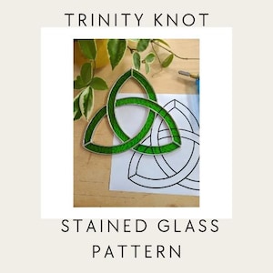 May include: A green stained glass Trinity Knot, with the text "TRINITY KNOT" above and "STAINED GLASS PATTERN" below. The knot is on a white paper with a black outline of the same design.