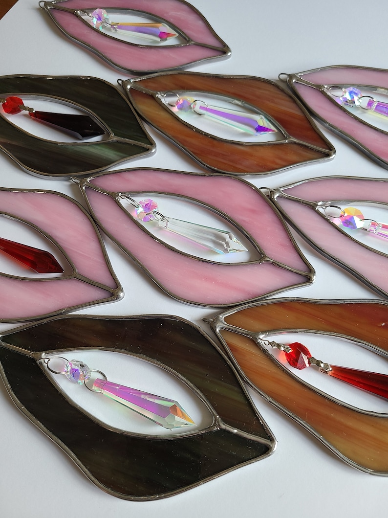 Puede incluir: Un conjunto de ocho adornos de vidrio de colores en forma de labios con detalles de cristal. Cada adorno presenta un color y un dise&ntilde;o diferente, incluyendo rosa, marr&oacute;n, negro y rojo.