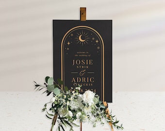 May include: Black wedding welcome sign with gold lettering and a moon and stars design. The sign reads "Welcome to the wedding of Josie Strik & Adric Vinckis 04.08.2024".