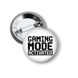 May include: A white button with the text "GAMING MODE ACTIVATED" in black, pixelated font. The button has a metal pin backing and a shiny silver rim. The button is a fun accessory for gamers.