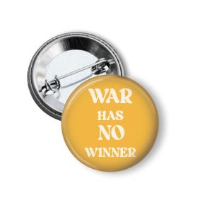 May include: A round, yellow button with the text "WAR HAS NO WINNER" in white. The button has a metal pin back. The button is a statement piece.