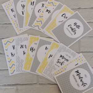 Pu&ograve; includere: Una collezione di biglietti di pietre miliari grigi, gialli e bianchi con scritte nere. Le carte hanno bordi a motivi. Le frasi includono "Hello Cankles" e "First Midwife Appointment Today".