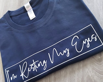 May include: A navy blue t-shirt with a white graphic that says "I'm Resting My Eyes" in a white rectangle.